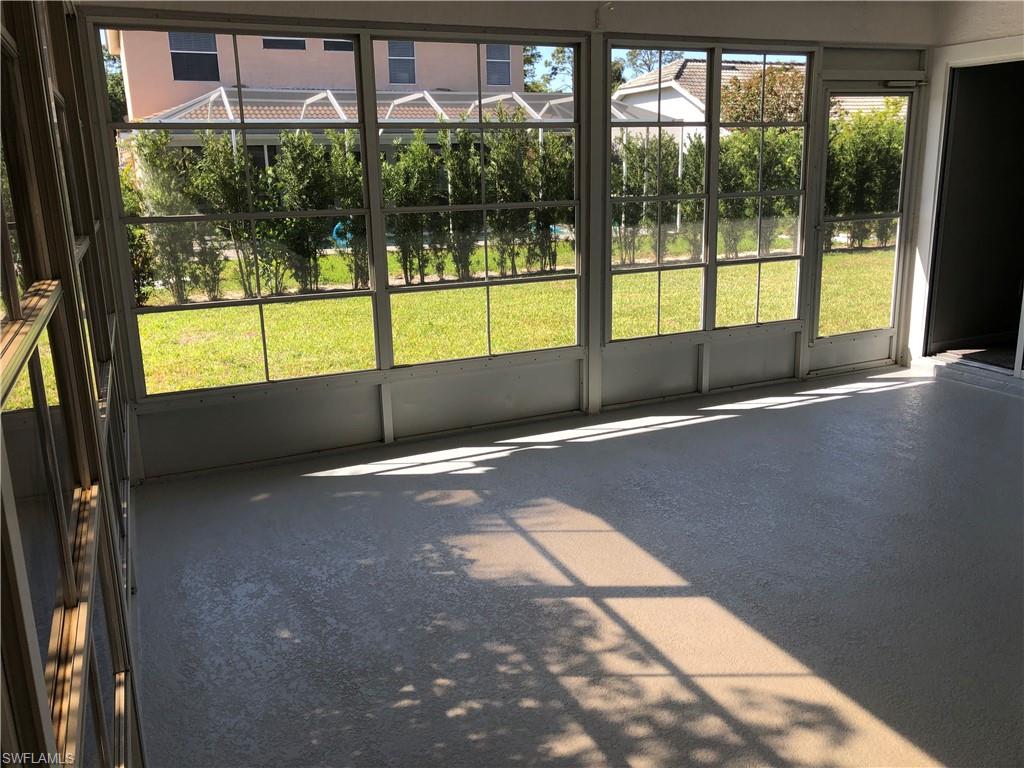 Screened patio featuring a textured floor, multiple framed window panels, and a hinged screen door