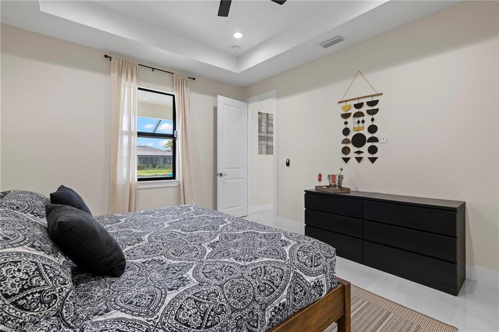 Tiled bedroom with ceiling fan and a tray ceiling