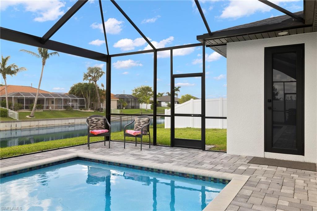 View of pool with glass enclosure, a patio area, and a lawn