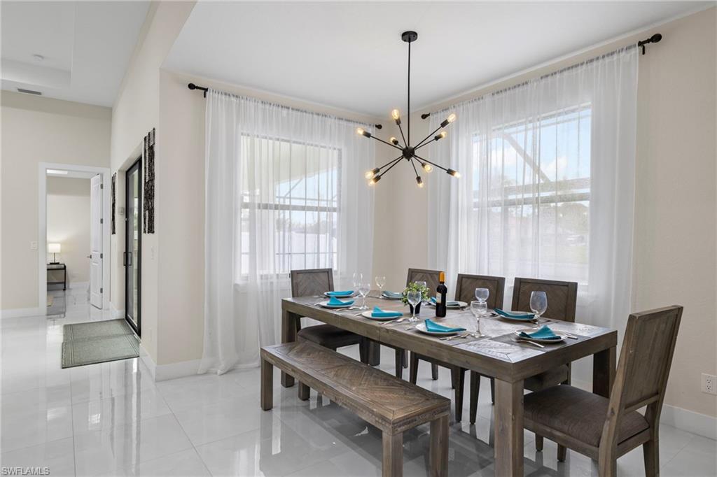 Dining room featuring light tile patterned floors, a notable chandelier, and plenty of natural light