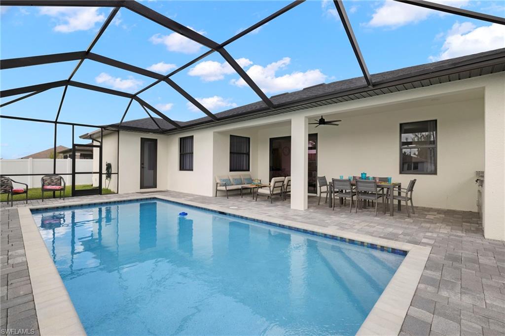 View of swimming pool featuring ceiling fan, outdoor lounge area, a patio area, and a lanai