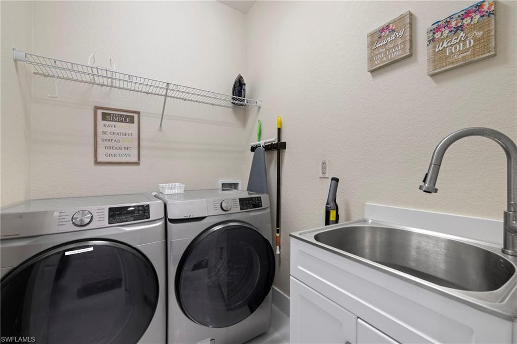 Washroom with washing machine and dryer, sink, and cabinets