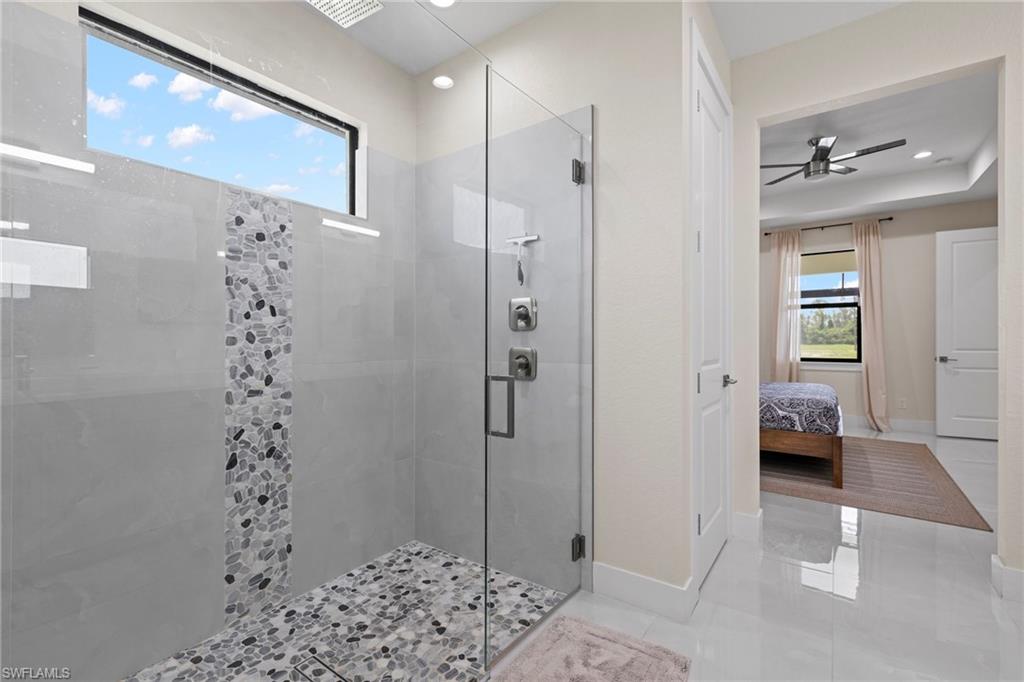 Bathroom with ceiling fan, an enclosed shower, and tile patterned flooring