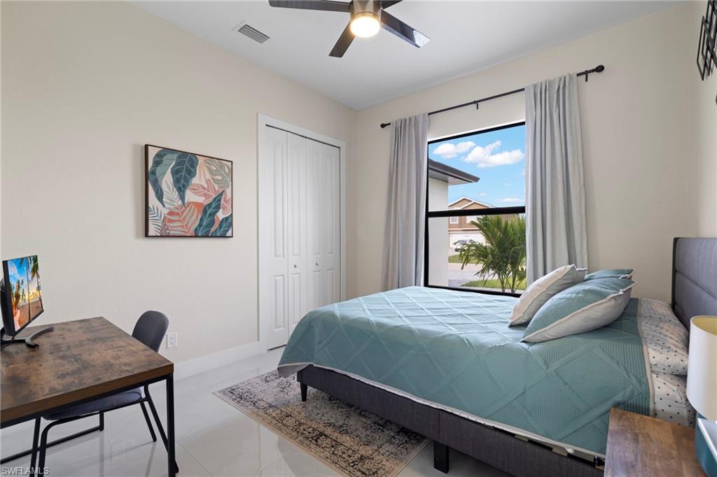 Tiled bedroom featuring ceiling fan and a closet