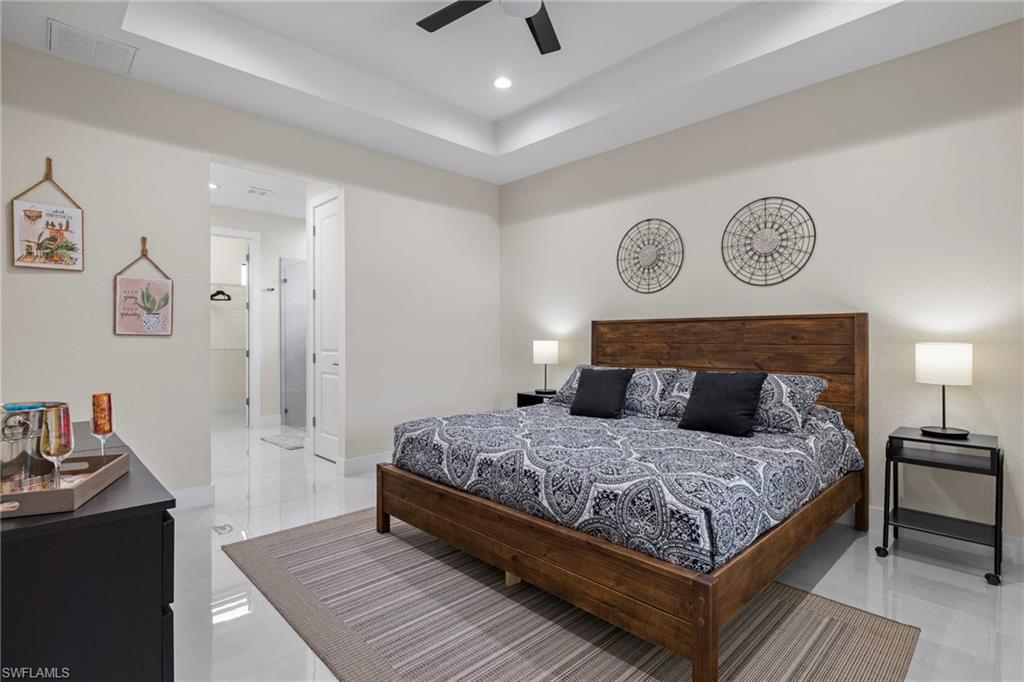 Bedroom featuring light tile patterned floors, ceiling fan, and a tray ceiling