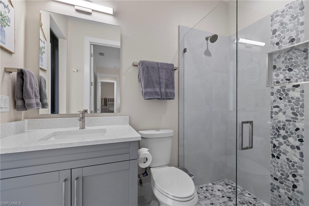 Bathroom featuring an enclosed shower, toilet, and vanity