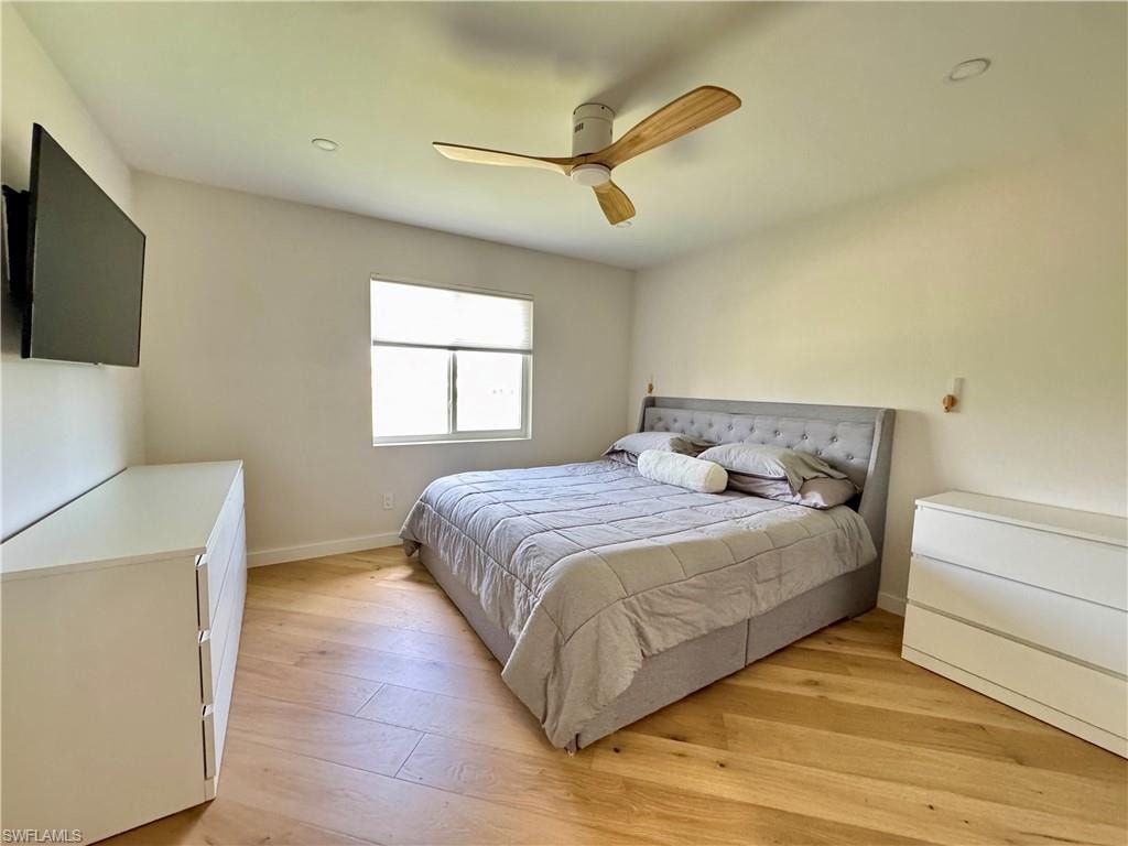Bedroom with light wood-type flooring, baseboards, and a ceiling fan