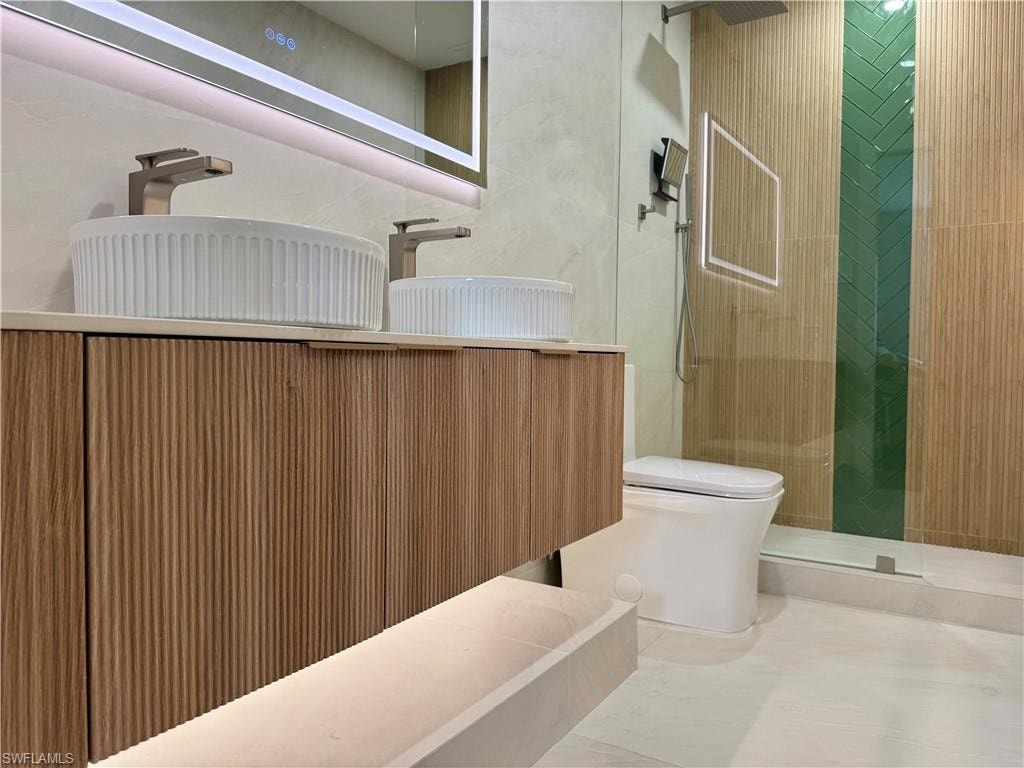 Bathroom featuring toilet, a tile shower, and vanity