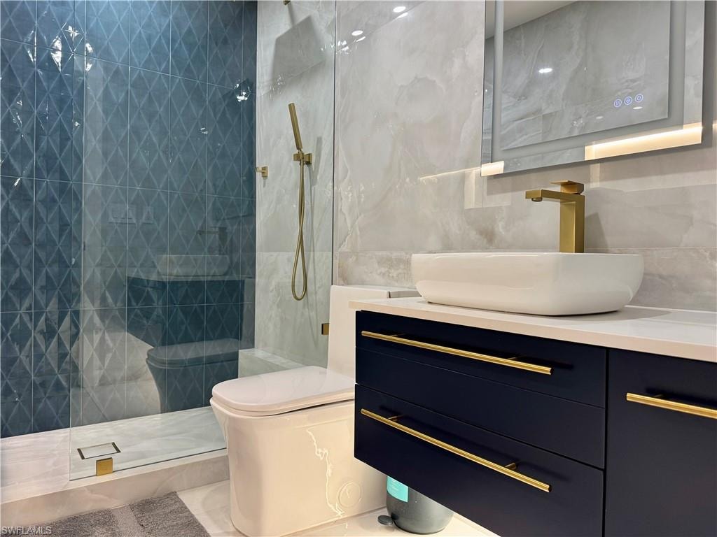 Full bath featuring tile walls, vanity, toilet, and a walk in shower