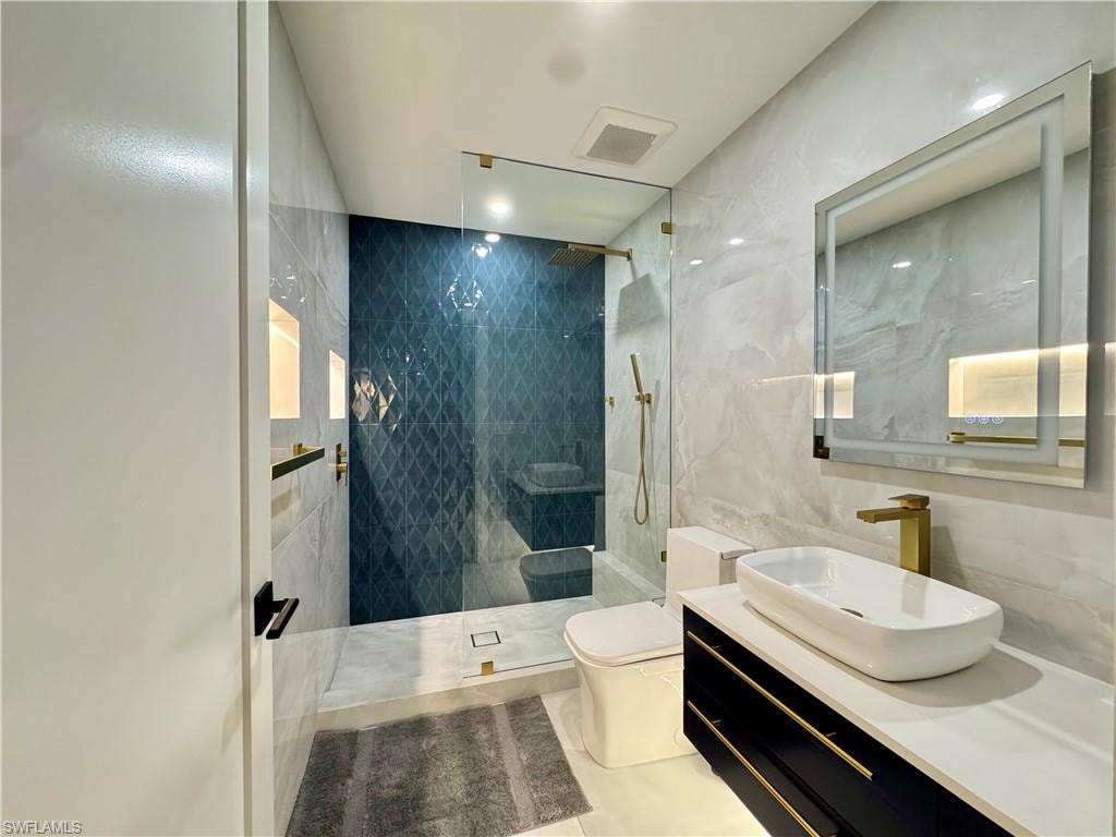 Full bath featuring toilet, walk in shower, tile walls, vanity, and tile patterned floors