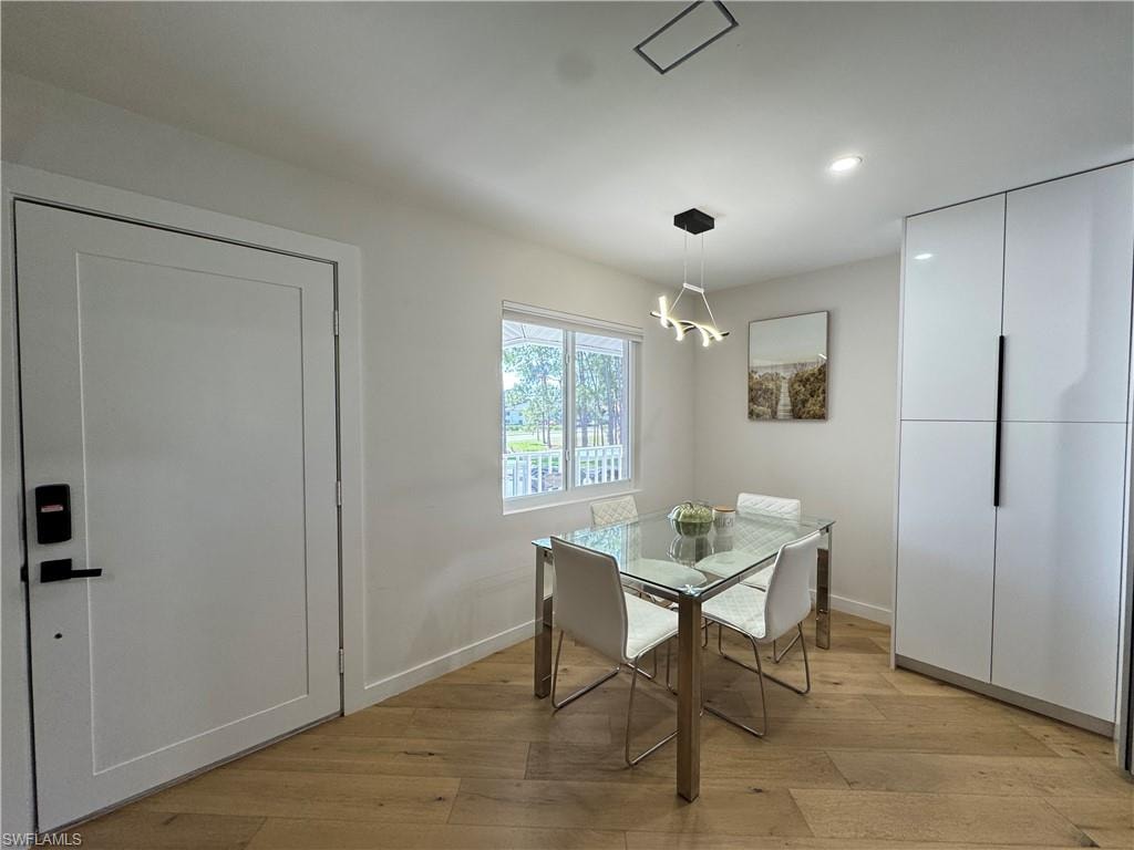 Dining area featuring light wood-type flooring, baseboards, recessed lighting, and a chandelier
