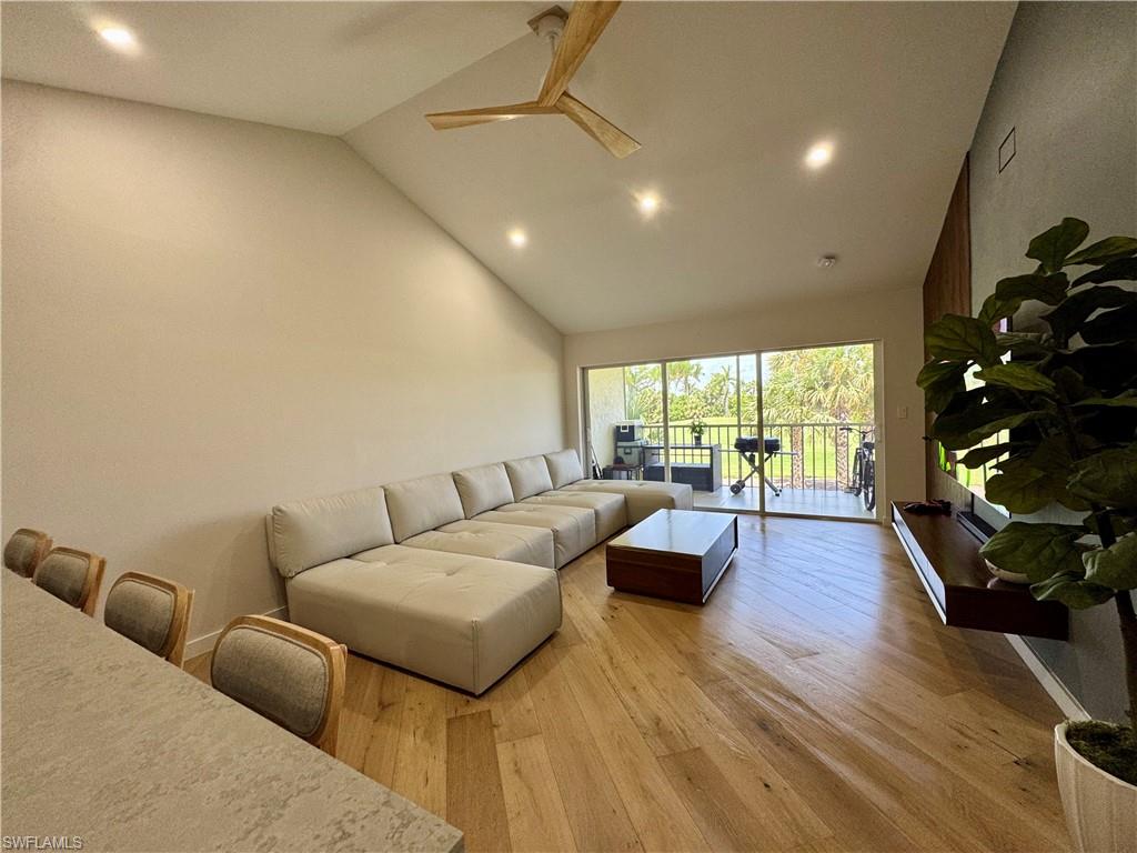 Living room with light wood-style flooring, recessed lighting, ceiling fan, and high vaulted ceiling