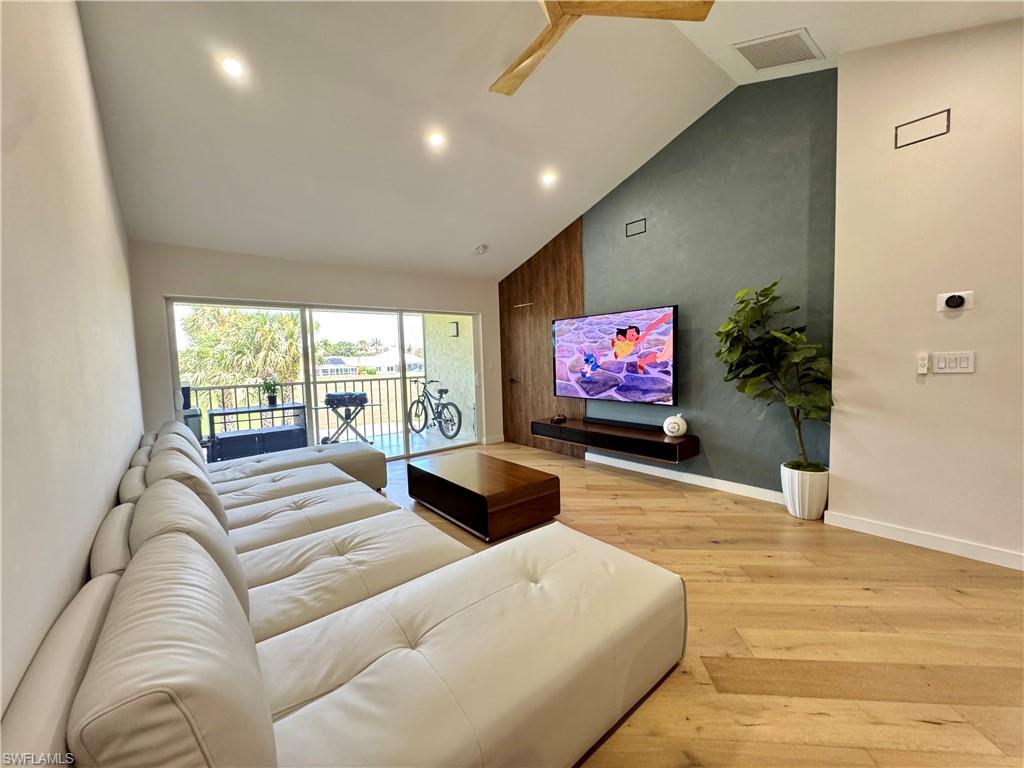 Living area with light wood finished floors, high vaulted ceiling, baseboards, and recessed lighting