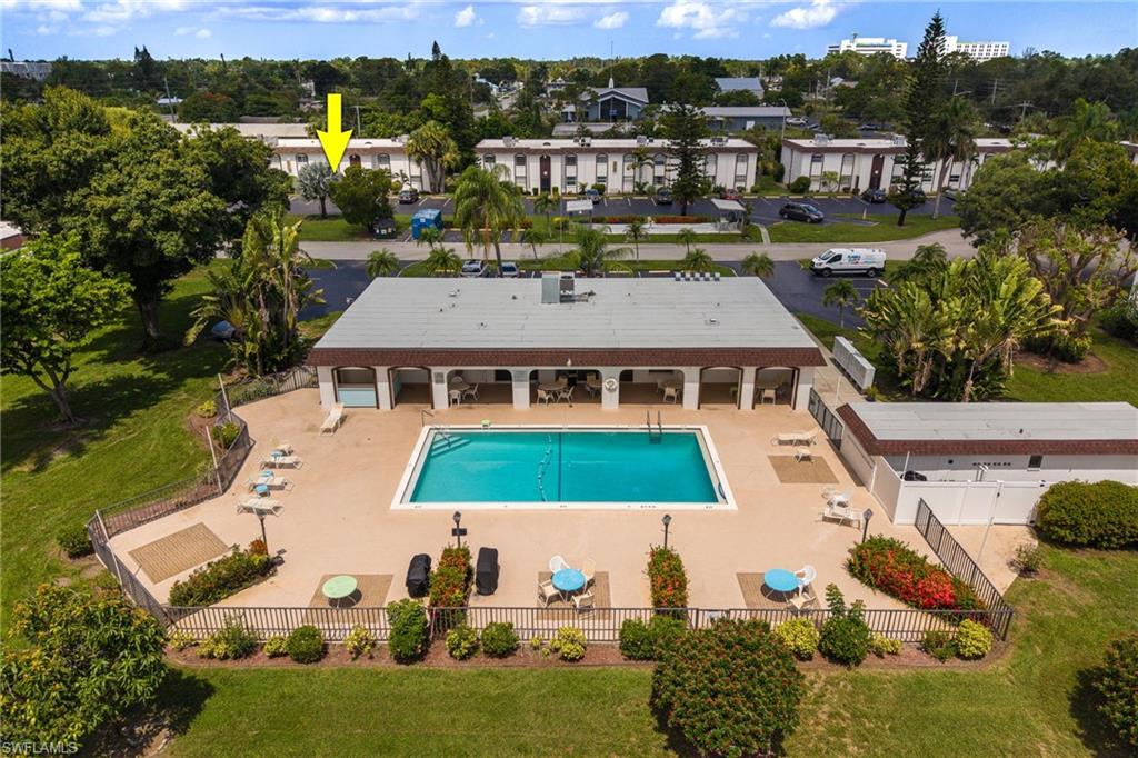 Clubhouse and community swimming pool with surrounding patio, fenced perimeter, arrow shows the unit location