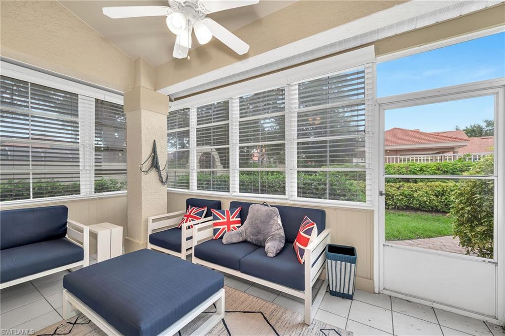 Screened porch featuring a white ceiling fan with integrated lighting, white-framed windows with blinds, a screen door, and tile flooring