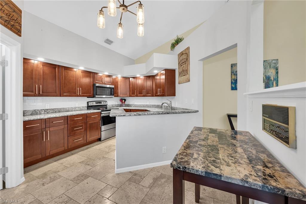 Kitchen featuring dark wood cabinetry, light-colored granite countertops, and a subway tile backsplash