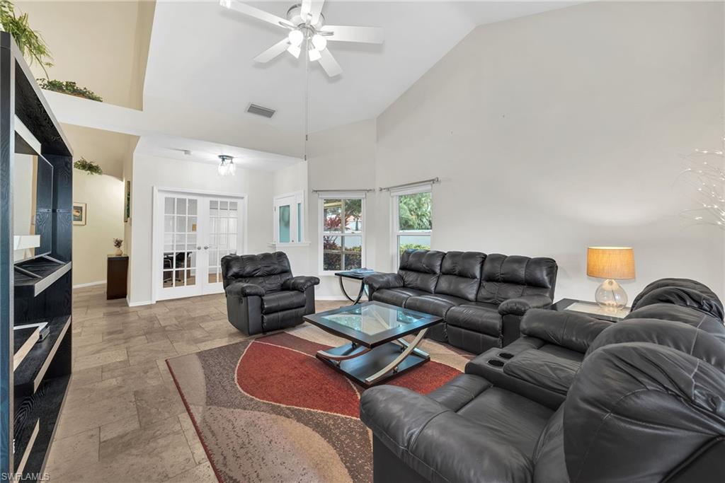Living area featuring high vaulted ceilings, ceiling fan, tile flooring, and white French doors