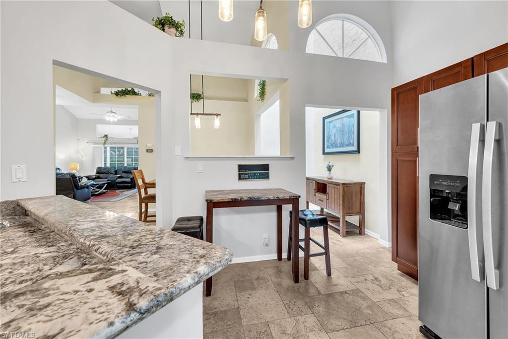 Kitchen featuring stainless steel refrigerator, warm wood cabinetry, and a granite-style countertop
