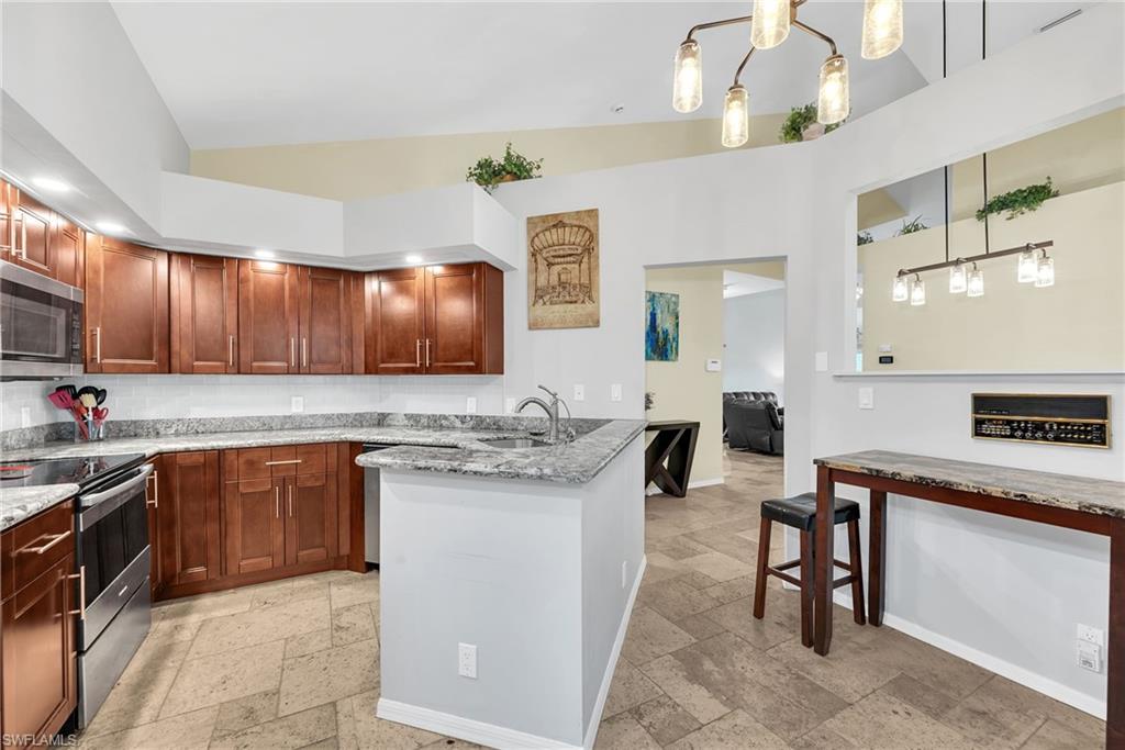 Open-concept kitchen featuring wood cabinetry, stainless steel appliances, and a double basin sink