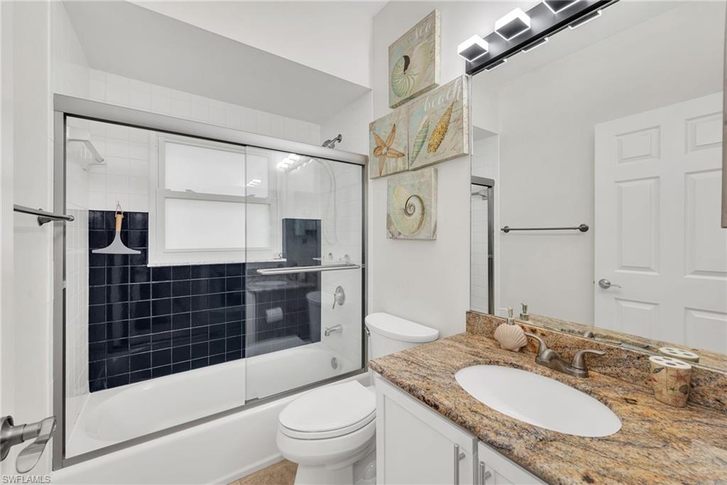 Bathroom featuring a white tub with dark tiled surround and sliding glass doors