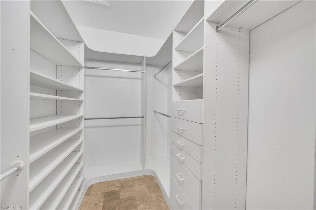 Custom walk-in closet featuring white built-in shelving, multiple hanging rods, and integrated drawers with white pulls
