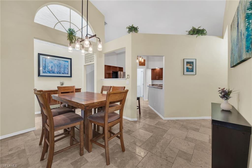 Open concept dining area with high ceilings, featuring a contemporary multi-bulb linear pendant light fixture