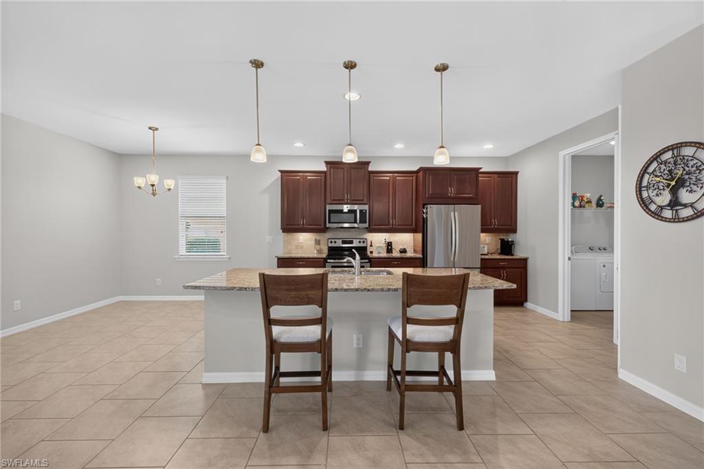 Open-concept kitchen featuring dark wood cabinetry, stainless steel appliances, and a central island with a granite-style countertop