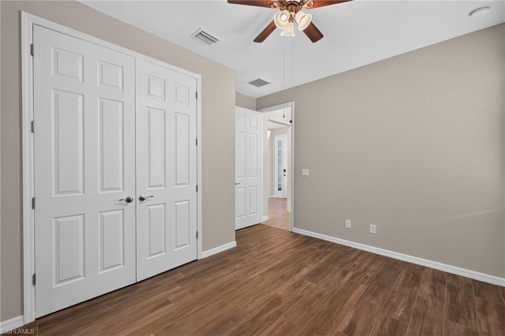 Room featuring wood-finish flooring, neutral wall paint, and a ceiling fan with integrated lighting