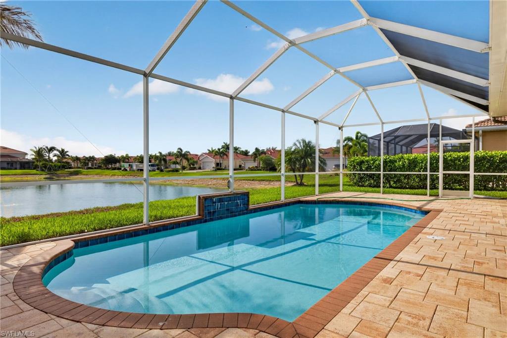 Screened outdoor pool area featuring a built-in pool with a water feature, paver deck, and perimeter landscaping