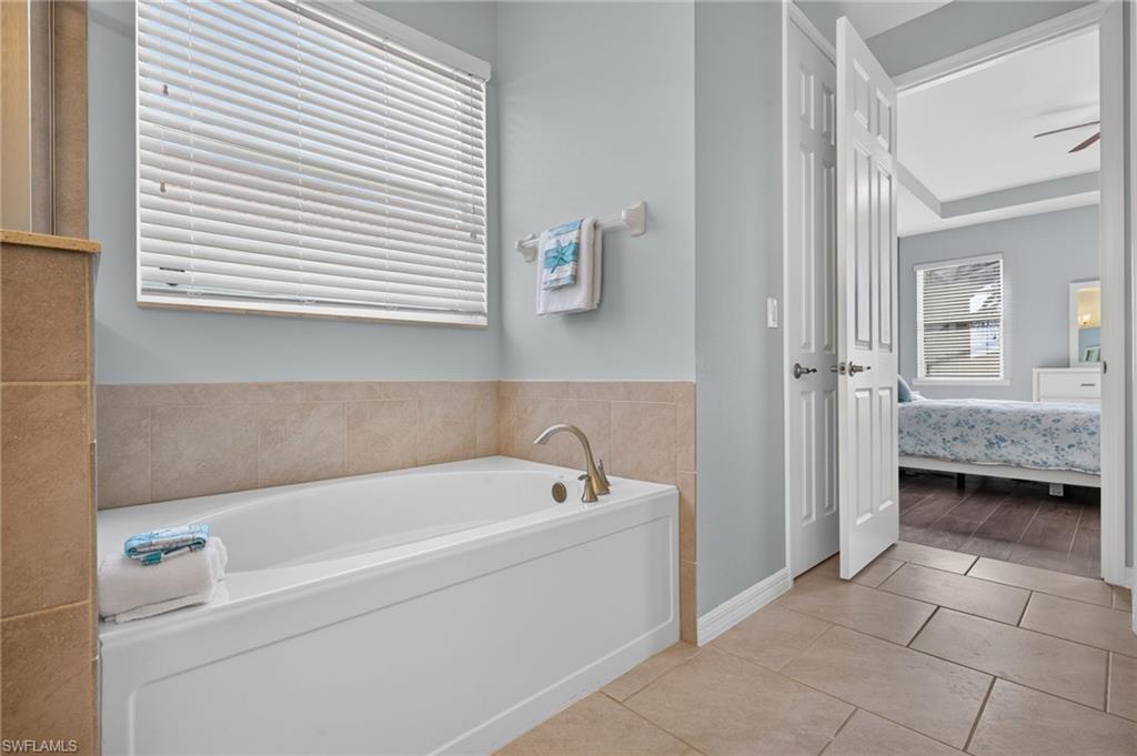 Soaking tub with brushed nickel fixtures and a tiled surround
