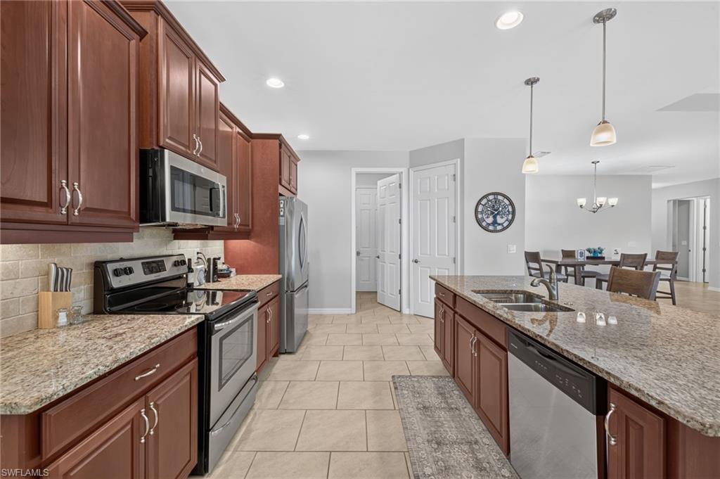 Kitchen featuring rich wood cabinetry, granite countertops, stainless steel appliances, and a tile backsplash