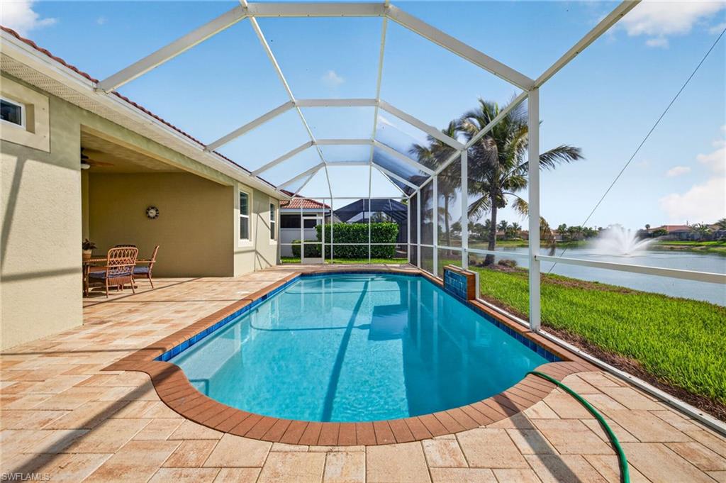 Screened-in swimming pool featuring a curved design and a water feature