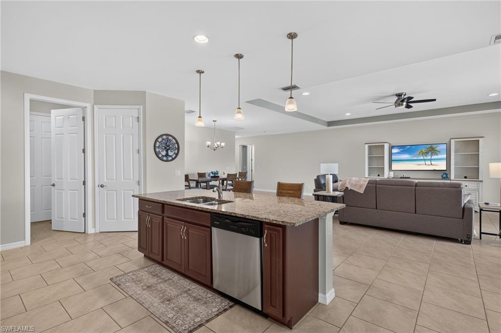 Kitchen island with granite countertop, integrated sink, and stainless steel dishwasher