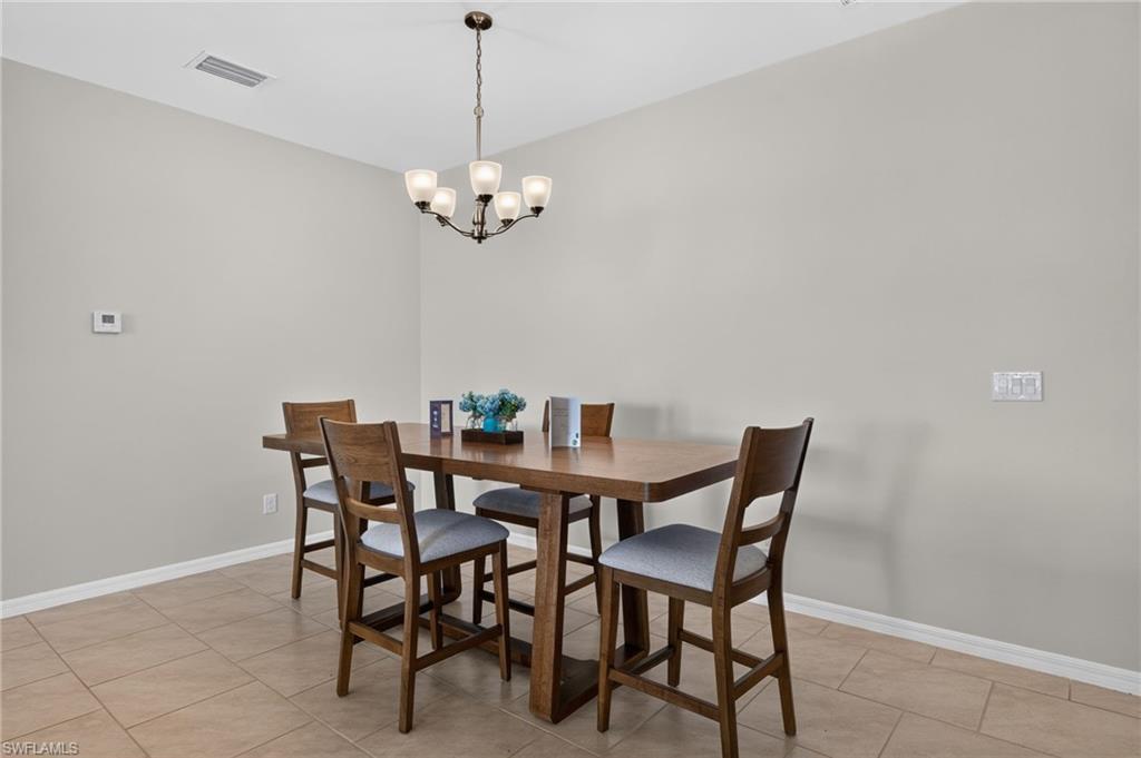 Recessed lighting, a chandelier light fixture, and tile flooring complement the light-toned walls