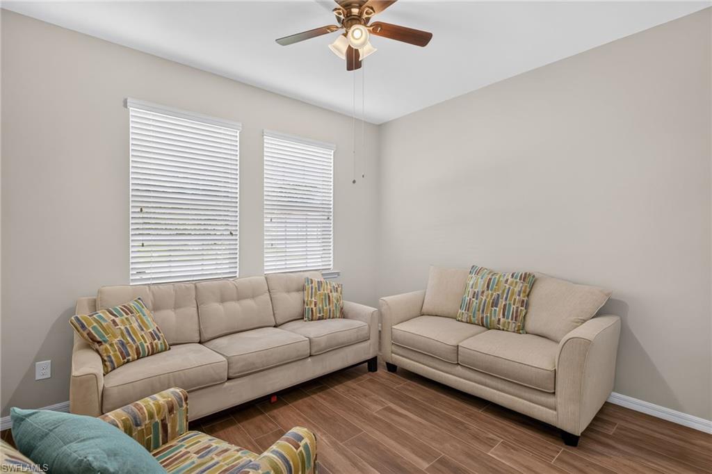 Bright room featuring two windows with horizontal blinds, wood-finish flooring, a ceiling fan with integrated lighting, and neutral wall tones