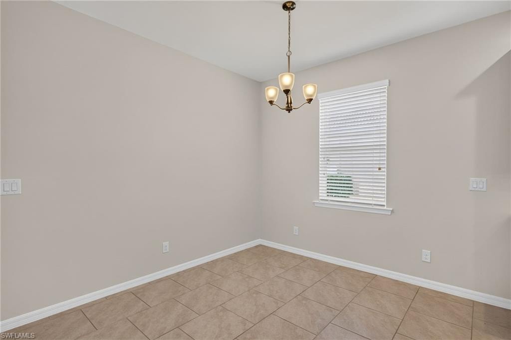 Dining area featuring a bronze-finish chandelier with three lights, a window with white blinds, and light-toned tile flooring