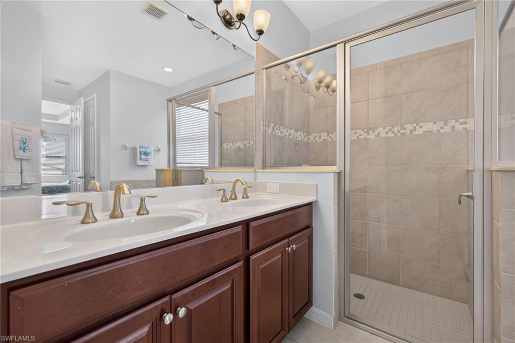 Dual vanity with white countertops, undermount sinks, and brass-finish fixtures