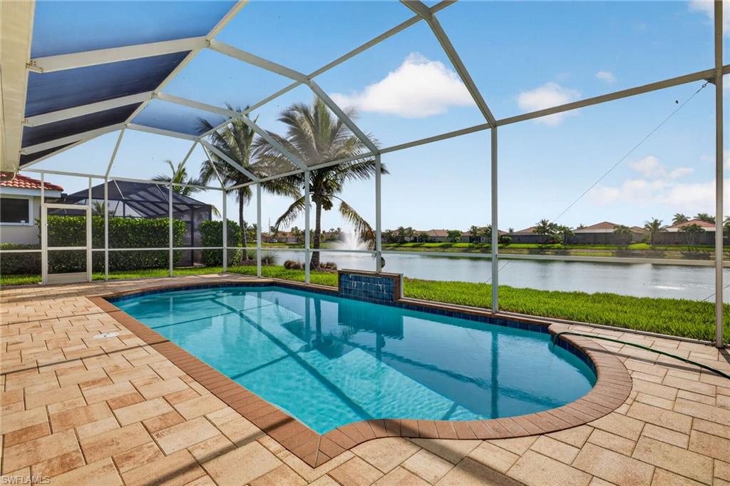 Screened lanai featuring a swimming pool with a decorative waterfall, paver patio, and direct waterfront access