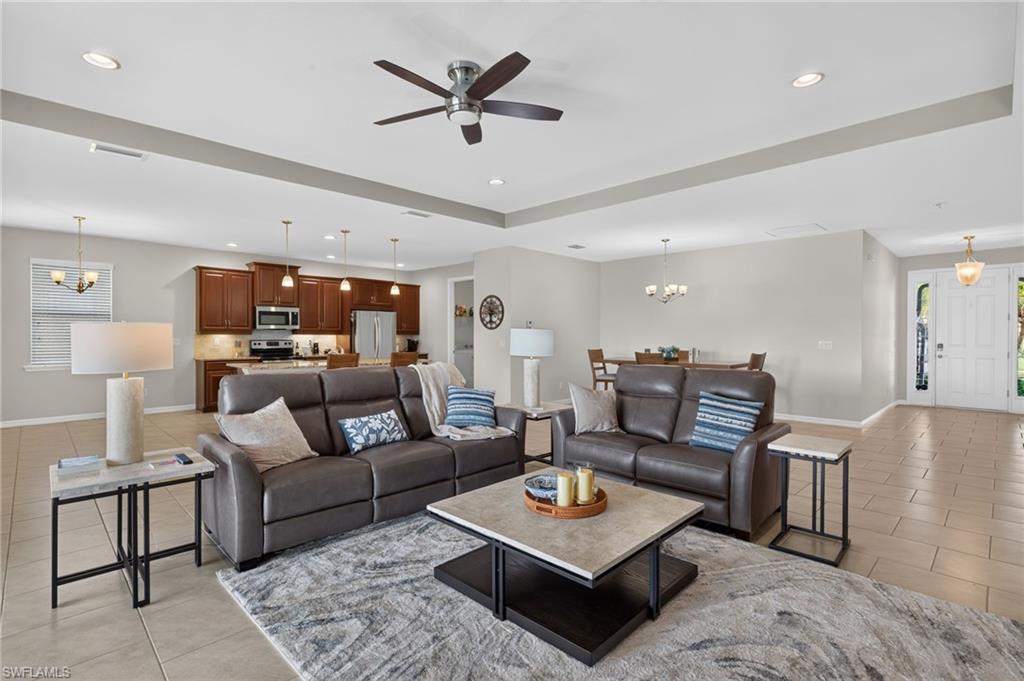 Open-concept living space featuring neutral tile flooring, recessed lighting, and a ceiling fan