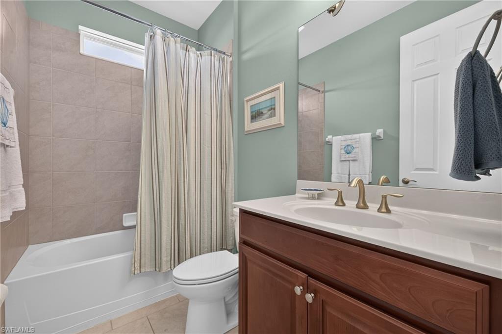 Bathroom featuring a vanity with a white countertop, undermount sink, and brass-finish faucet
