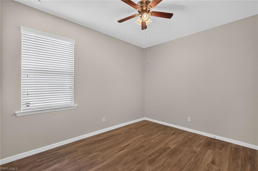 Room with wood-finish flooring, neutral wall paint, and white baseboards