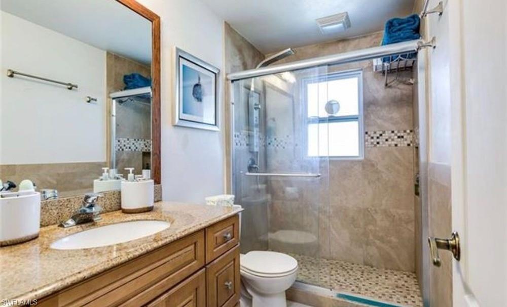 Bathroom featuring a single vanity with a granite-style countertop, wood-finish cabinetry, and a chrome faucet