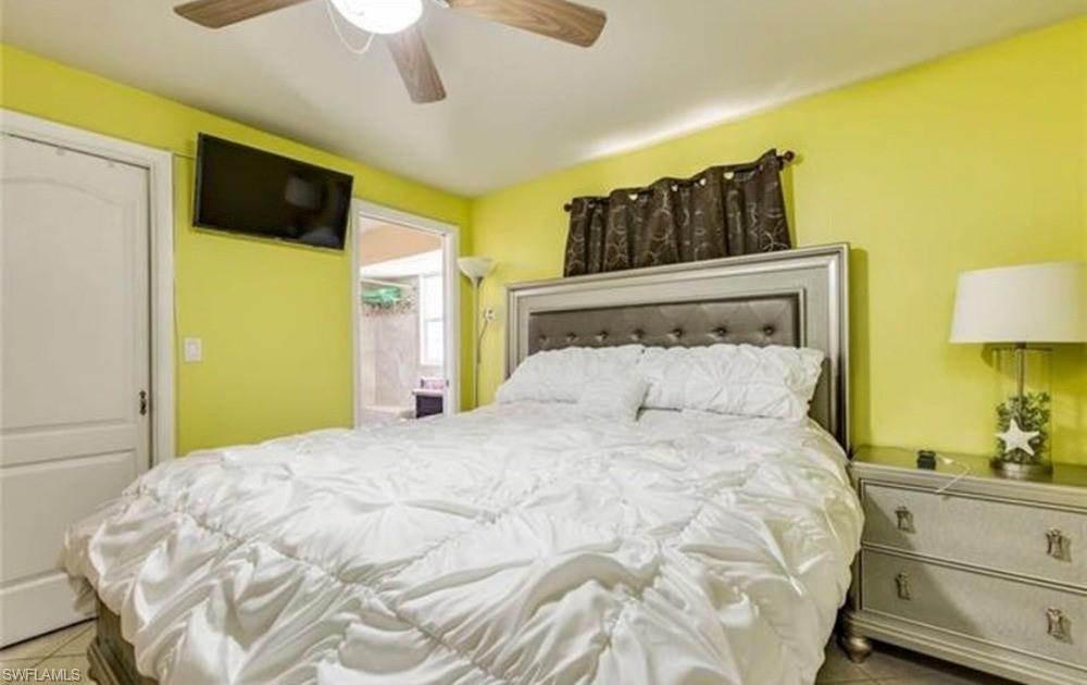 Bedroom featuring a ceiling fan, wall-mounted television, and an upholstered headboard