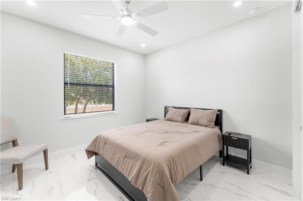 Bright interior space featuring a window with horizontal blinds, overhead ceiling fan with lighting, recessed lighting, and white tile flooring