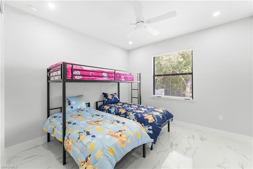 Bright room featuring large window with horizontal blinds, overhead ceiling fan, recessed lighting, and white baseboards with polished tile flooring