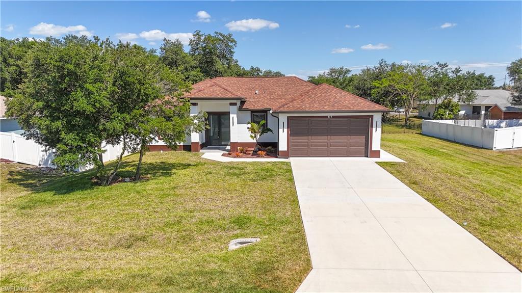 Contemporary stucco exterior featuring a terracotta-hued tile roof, an attached two-car garage with a wood-finish door, a paved driveway, and a welcoming front entrance with double glass doors