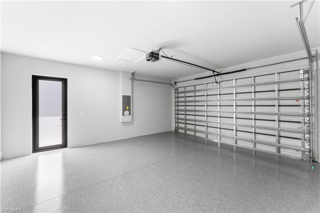 Spacious garage featuring a durable epoxy-coated floor, a large overhead garage door, and a separate full-lite exterior door