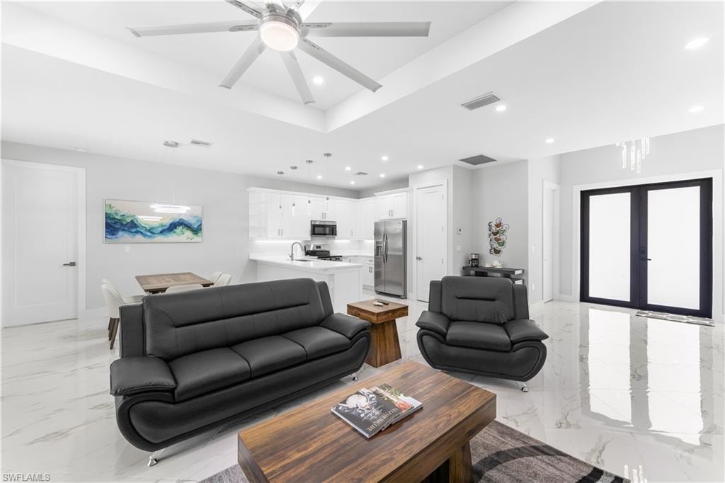Open-concept living area featuring a coffered ceiling with a ceiling fan, recessed lighting, and large format polished tile flooring