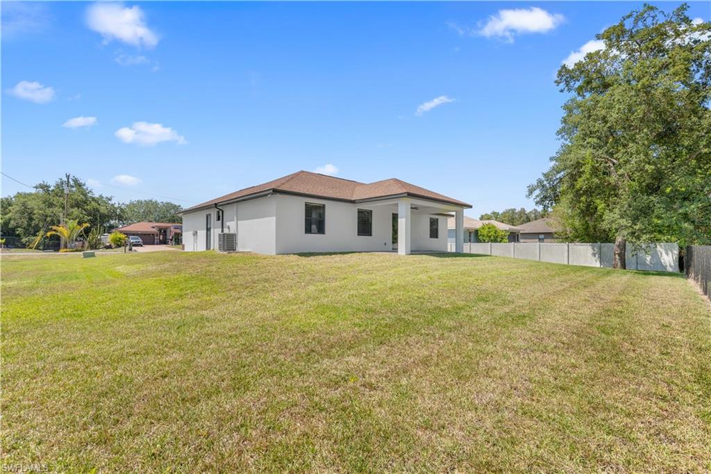 Expansive backyard featuring a lush lawn and a concrete block privacy fence