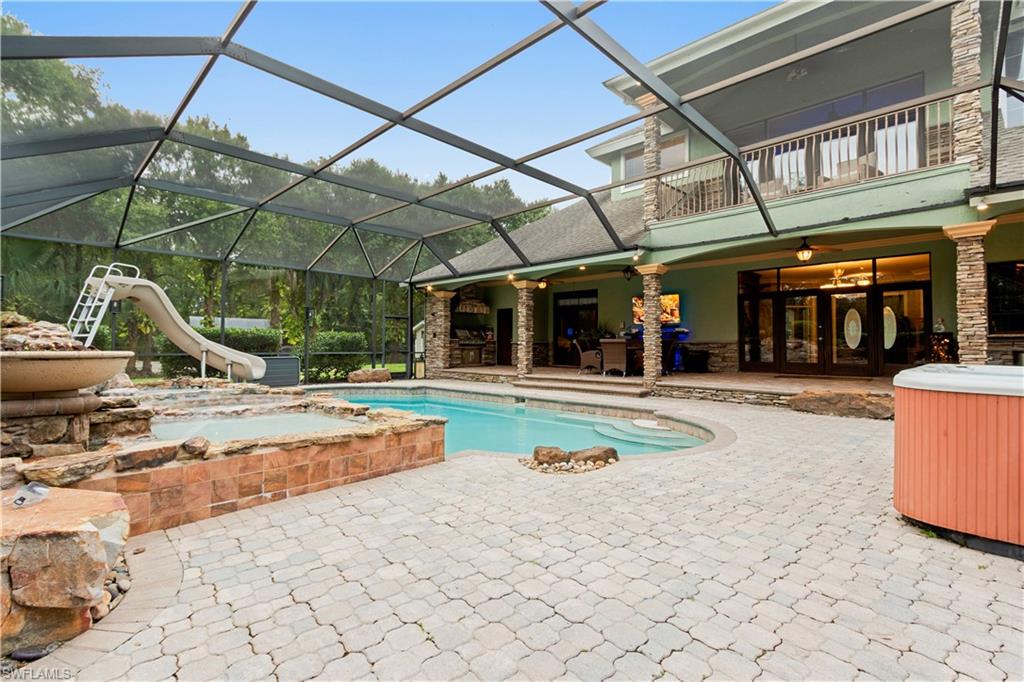 Screened paver patio featuring a swimming pool, integrated spa, and rock waterfall feature